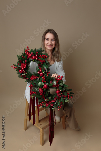 Smiling Woman Posing with a Festive Red and Green Christmas Wreath