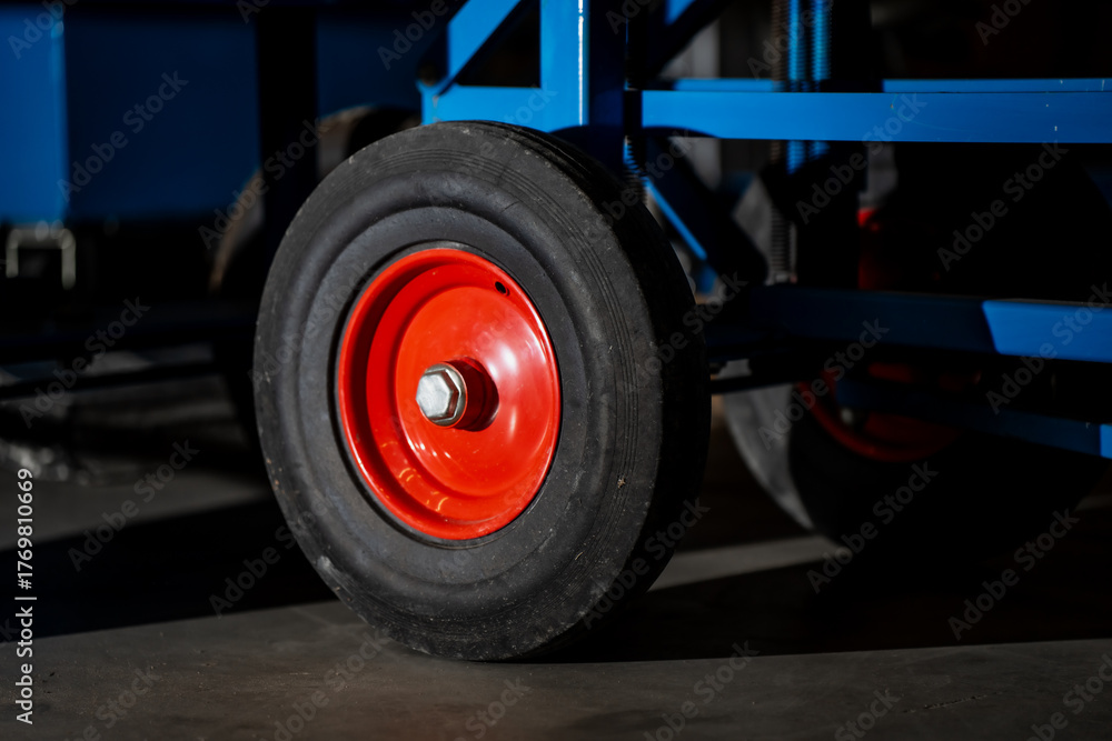 Fototapeta premium Industrial transport wheel showing red metal hub and rubber tire representing warehouse mobility, logistics tools, material handling and manufacturing equipment