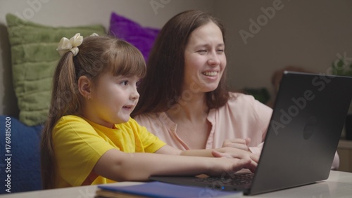 cheerful happy mom with child doing homework laptop. american education online. teamwork. happy family. child kid daughter hugs parent mother. together to win going to success. maternal care love kid.