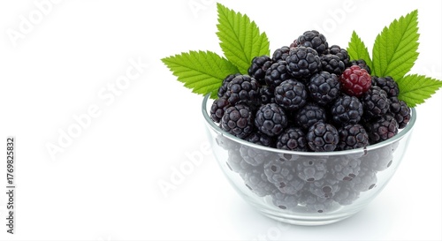 fresh blackberries with green leaves in a glass bowl on a white background, healthy snack concept