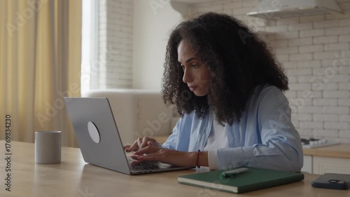 Focused Woman Working Remotely On Laptop At Home Kitchen Table