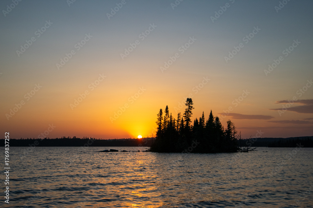 Fototapeta premium silhouette of a small island against an orange sunset sky Ontario Canada