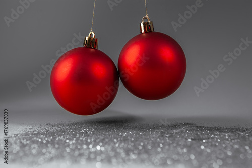 Two red christmas balls on silver glitter background, close-up