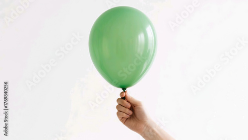 Wallpaper Mural A hand holding a green balloon against a white background. Simple and clean image suitable for various themes. Torontodigital.ca