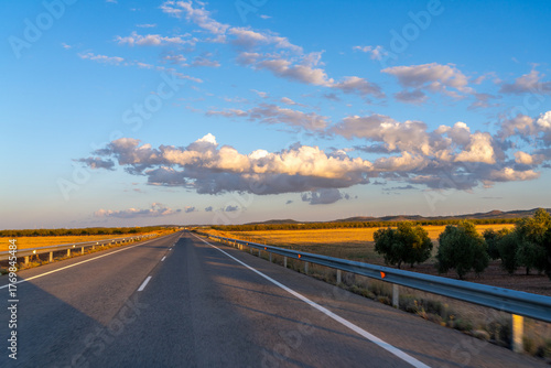 Open road under a cloudy sky at sunset.