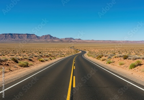 Winding asphalt road cuts through a vast, desolate desert landscape under a clear blue sky, emphasizing isolation and journey ,view ,asphalt ,vanishing