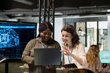 Powerful team of diverse associates review AI generated analytics from TV monitor, applying machine learning tools and neural networks to drive development and achieve corporate goals.