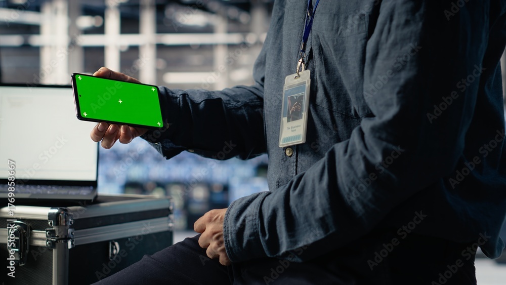 Obraz premium Data center worker uses isolated screen smartphone while deploying deep learning software. Server hub employee uses chroma key mobile phone while training AI systems with datasets, camera B