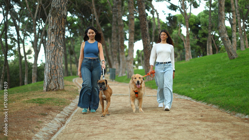 Women walking dogs in park, enjoying friendship and leisure