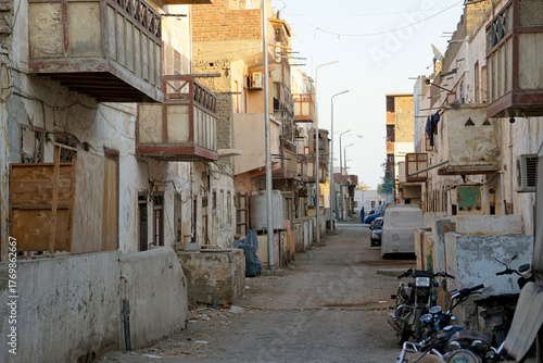 Narrow, dirty dirt road between crumbling multi-story buildings