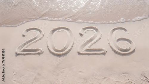 The year two thousand and twenty six written in the sand with a wave washing over the number