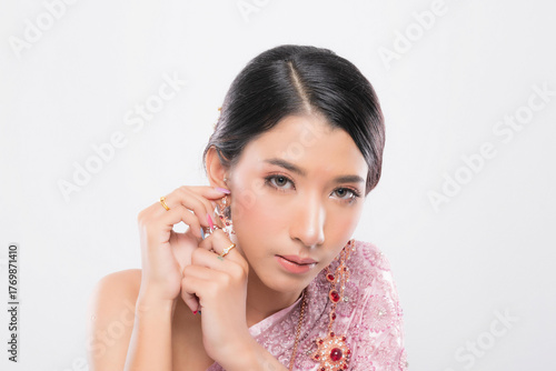 Captivating portrait Asian woman wear pink traditional attire and exquisite gold and ruby jewelry at studio shot on white background.