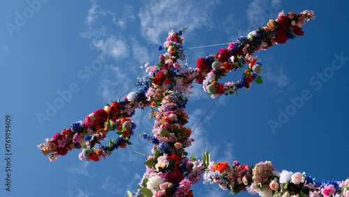 Colorful midsummer pole decorated with flowers against blue sky