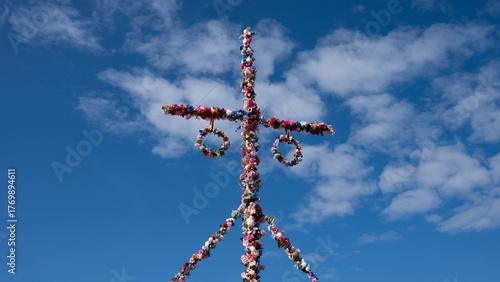 Traditional midsummer pole decorated with flowers under blue sky