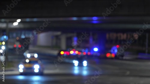 Abstract blurred night road scene with glowing emergency vehicle lights and soft bokeh, creating a cinematic urban atmosphere suitable for backgrounds, design, news graphics and motion visuals
