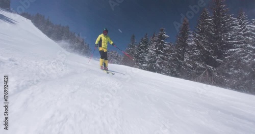 Skier glides through fresh powder on scenic mountain slope beneath clear blue sky