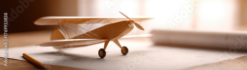 Wooden model airplane on blueprint with pencil in warm light creating nostalgic mood