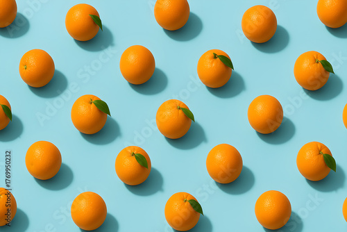 Repeating pattern of oranges with leaves on a light blue background creating a vibrant composition