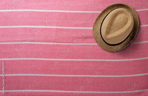 Stylish Straw Hat Resting on a Pink Striped Beach Towel. File with Clipping Path.