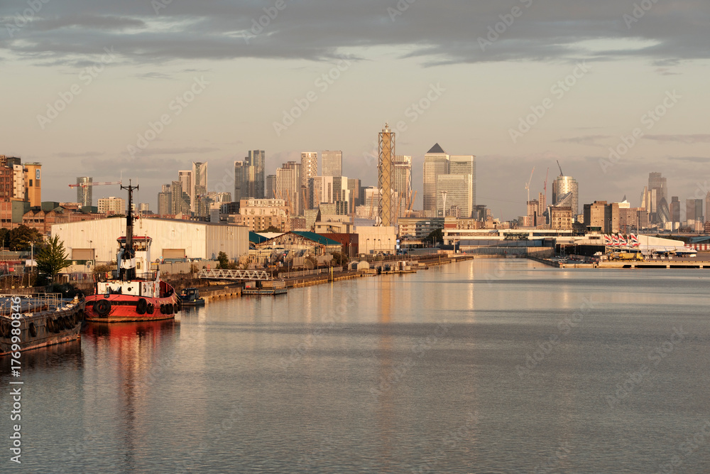 Fototapeta premium London canary wharf cityscape with tugboat on river thames at sunrise