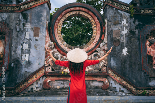 Young woman in red dress praying at Buddhist temple during Spring Festival, back view