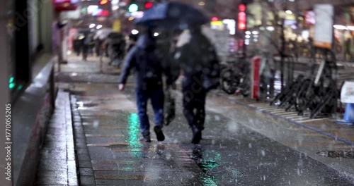 Walking people at business town in Shinjuku snowy day handheld at night