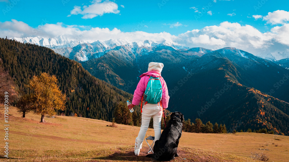 Naklejka premium Asian woman as her dog rest and enjoy of the view as sitting on a chair. Hiking in nature. in Mestia Mountain ,Georgia