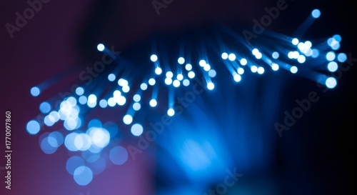 Abstract macro shot of illuminated fiber optic cables, creating a modern blue and white bokeh effect, representing data transmission, internet, and technology with a dark background.