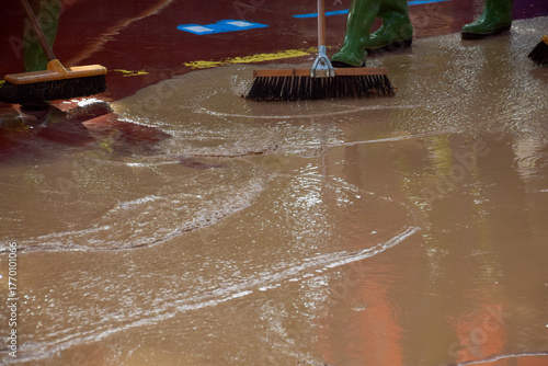 Workers remove mud after a road passes with brushes and pressuri