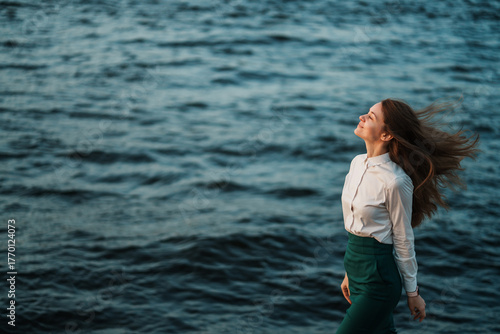 Foto A woman in profile gracefully walks by a vibrant seascape, her hair flowing in the breeze, exuding a sense of tranquility and freedom