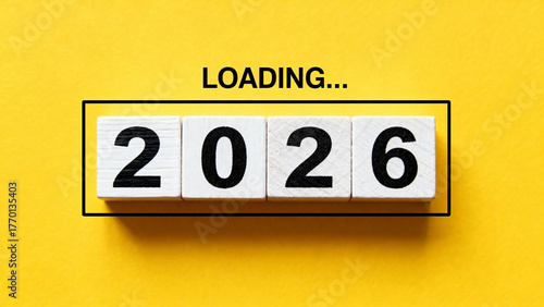 Wooden blocks displaying '2026' with 'LOADING...' text above on a yellow background