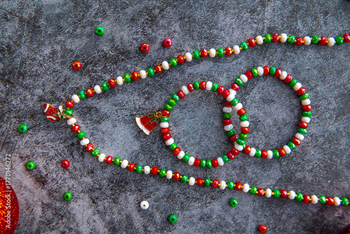 Christmas themed handmade necklace and bracelets on a stone background surrounded by Christmas balls.