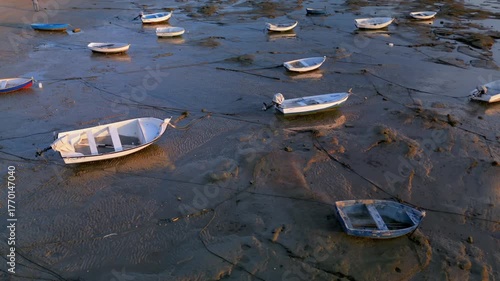 Low-altitude aerial view of boats at low tide on the seaside, breathtaking summer sunset landscape.