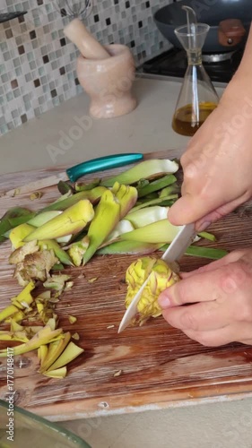 Anonymous person peels artichoke in kitchen at home. Healthy eating and traditional Italian dish. Fresh seasonal farm produce.