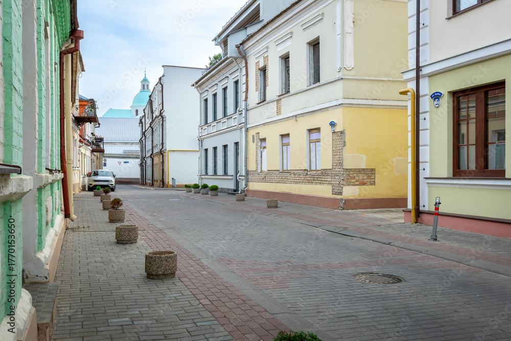 Fototapeta premium Quiet old European street with historic buildings and car parked near the sidewalk