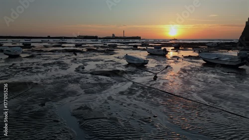 Low-altitude aerial view of boats at low tide on the seaside, breathtaking summer sunset landscape.