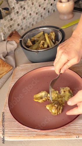 Anonymous person make creamy puree from boiled artichokes on plate on kitchen counter at home. Healthy eating and traditional Italian dish. Seasonal farm produce.