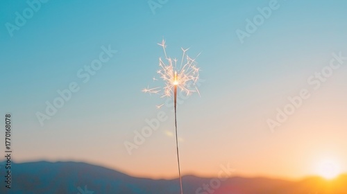 Sparkler Glowing in Sunset with Mountains in Background Creating Festive Atmosphere for Celebrations and Events