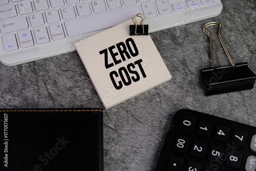 calculator and white note pad with text ZERO COST as a financial and business concept on red background.