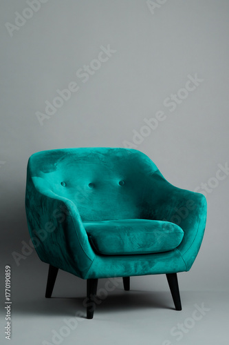 Comfortable Turquoise green armchair behind grey background. Interior design furniture