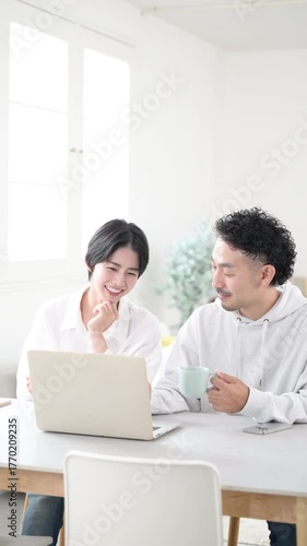 綺麗なリビングでダイニングパソコンを見ながら話す夫婦　幸せな結婚のイメージの縦動画