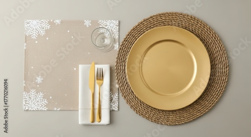A gold charger plate on a woven placemat with a snowflake napkin and cutlery