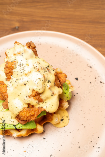 Fried chicken with avocado slices and creamy hollandaise sauce