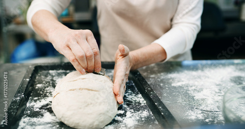 Hands, score dough or bread in bakery with blade for cooking food, restaurant cuisine or hospitality. Person, knife or ingredients in kitchen for catering, meal prep and gluten free sourdough recipe.