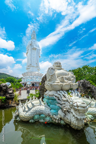 Smiling Buddha in front of Giant statue of the goddess Guan Yin or Kwan Im (The Lady Buddha) statue in the Linh Ung Pagoda Son Tra Peninsula, Da Nang.