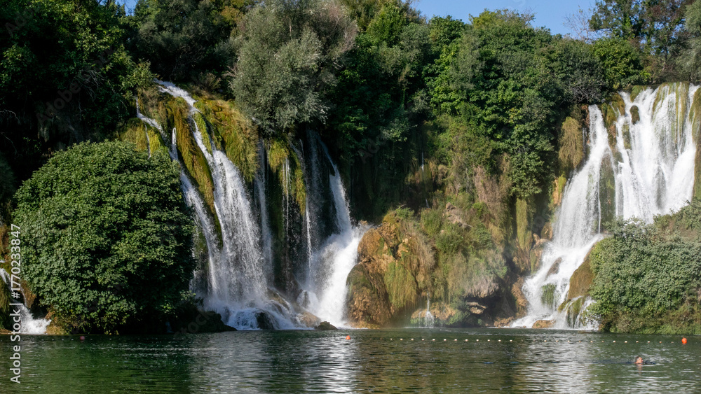 Fototapeta premium Cascading waterfalls whisper ancient secrets under the midsummer sun, evoking Beltane celebrations and serene nature retreats