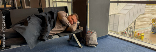 Quadro su tela Sleeping traveler, weary Caucasian male, embraces airport bench, an ode to jet l