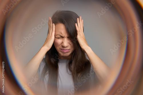 Woman closing eyes in pain suffering from migraine aura and sensory overload