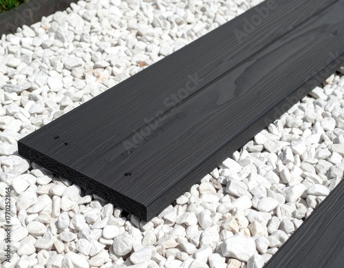 Dark gray plank of wood sits on a bed of white gravel