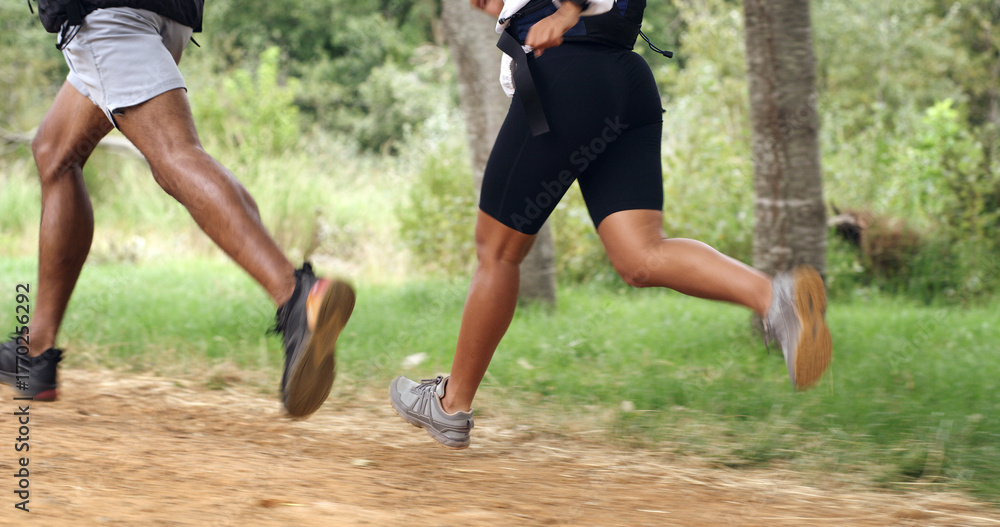 Fototapeta premium Fitness, legs and couple running in forest for health, wellness or training outdoor. Man, woman and shoes of trail runner in woods for cardio workout, endurance exercise and practice in nature